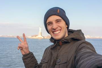 happy man taking a selfie from the new york ferry, Statue of Liberty as background © NDStock