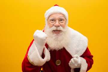 Holly jolly x-mas and Noel, confidence, magic, triumph concept. Cool funny playful grandfather with wide open mouth, comic grimace, fooling around isolated on yellow background, shows win gesture