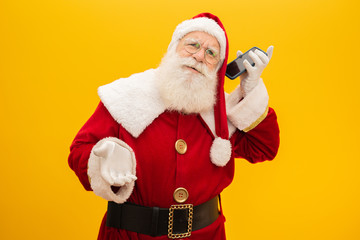 Santa Claus with cellphone on yellow background. Concept of communication, telephone companies and promotions.