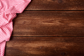 Flat lay of old wooden background with red checkered dishcloth