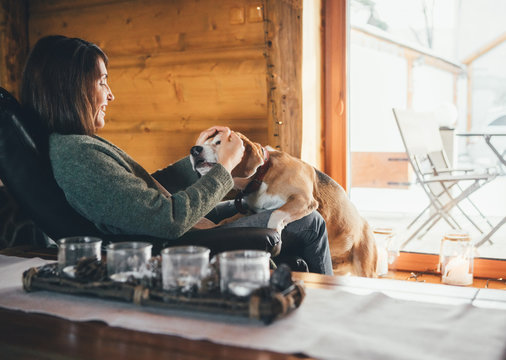 Tender scene with woman and her beagle dog in comfortable cozy country home. Countryside vacation with pets