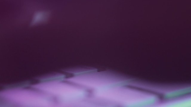 Close-up of Hand Typing Text or Internet Message on Keyboard in Pink Light. Slow Motion