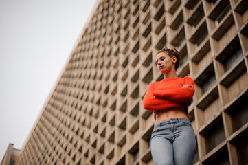 Woman in the orange sweater and jeans standing in the background of the concrete construction