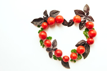  heart-shaped frame of cherry tomato, purple basil leaves and parsley on a white isolated background with place for text.