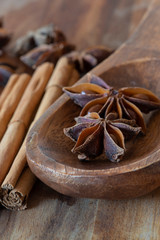 Star anise in wooden spoon with cinnamon on wooden chopping board. Aromatic spices