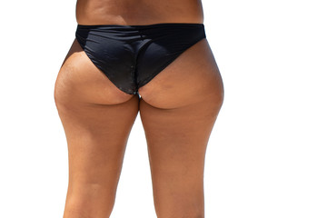 A closeup and rear view on the buttocks, legs and hips of a woman wearing a black bikini, enlarged...