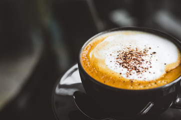 close up modern hot black coffee the cappuccino on dark background with coffee bubble foam pattern and texture in black cup looking and feel so delicious on glasses table in coffee shop.