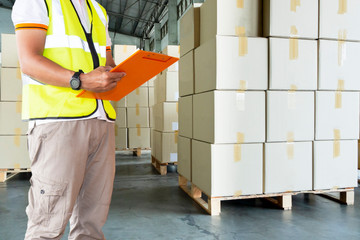 freight business industry delivery, warehouse inventory management, worker in uniform hand holding clipboard inspecting checklist details of cargo, stack cardboard boxes on wooden pallet.