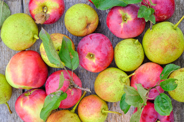 Fresh red apples with green leaves on a wooden old table.