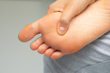 A close up view of a person rubbing and massaging the sole of their barefoot, near toes, achy and...