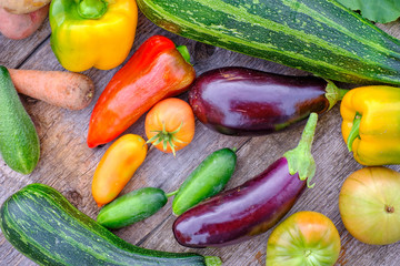 Still life of fruits and vegetables. Composition of zucchini, eggplant, tomatoes, cucumbers, peppers, carrots and potatoes. Vegetables are on an old wooden table.