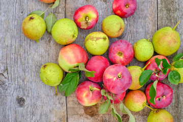 Fresh red apples with green leaves on a wooden old table.