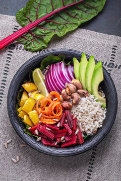 Vegetarian Buddha bowl with rice, swiss chard, cashew, avacado, squash, onion, carrot. Top view with copy space