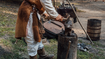 Senior blacksmith forging the molten metal on the anvil in smithy. Blacksmithing. Hammer and anvil. Blacksmith forging iron. Village craft. Blacksmith working metal. 