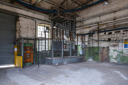 Interior view of open old dirty room with the controller zone of pressure sensors, pump station and metal pipe system on ceiling and wall in factory or industrial building.