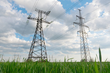 Electrical net of poles on a panorama of blue sky and green meadow