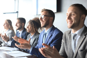 Photo of happy business people applauding at conference.