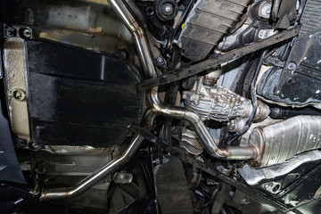 Fototapeta premium Fabrication and installation of a stainless steel car exhaust pipe with a bifurcation and a louder sound with a color weld under bottom. Tuning and auto service industry.