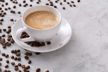 A cup of delicious hot cappuccino and beans on a gray concrete table