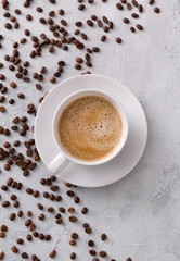 A cup of delicious hot cappuccino and beans on a gray concrete table