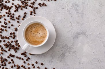 A cup of delicious hot cappuccino and beans on a gray concrete table