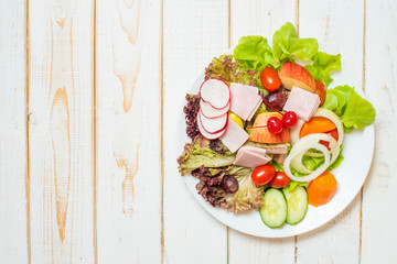 Vegetables salad on dish on white wood table
