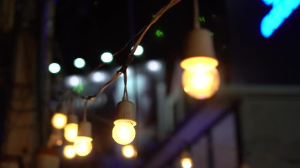Festival light bulbs garland in Asian night market with blue neon sign background