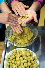 many caucasian female hands rolling and making falafel balls for a large group meal