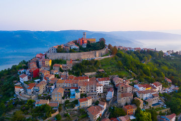 The ancient city of Motovun is located on the top of the mountain. The city is surrounded by a fortress wall. The background image are mountains and fog at the foot of the mountains. Istria, Croatia.