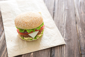 Delicious fast food. Homemade hamburger with lettuce, tomato, cheese and cucumber on a cutting board