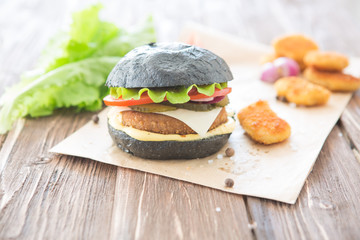 Delicious fast food. Two hamburgers with beef burger cutlet, fried onion, spinach, ketchup sauce and blue cheese in traditional buns, served on wood chopping board over dark wooden background.