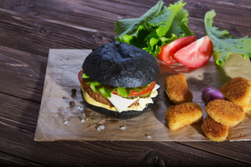 Delicious fast food. Tasty burger with bacon on table against black background. Space for text