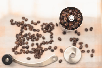 The coffee beans are in an antique hand-cranked coffee bean grinder, the kitchen tablecloth background in natural light, Selcetive focus, Vintage style.