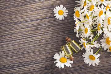 Glass bottle with essential aroma chamomile oil with flowers