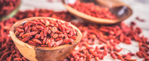Wooden bowl with goji berries on the table closeup