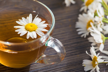 Glass cup with herbal tea with chamomile flowers