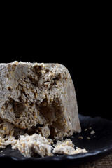 Big piece of sunflower and sesame halva on wooden table against black background. Eastern dessert