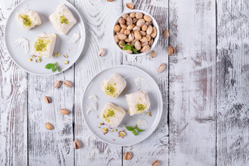 Cotton candy with pistachio on ceramic plate on white wooden table. Top view