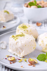 Cotton candy with pistachio on ceramic plate on white wooden table