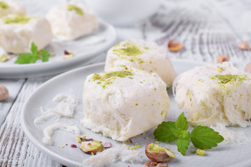 Cotton candy with pistachio on ceramic plate on white wooden table