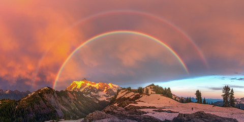 The rainbow over stormy mountains at dusk