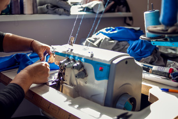 Woman works with sewing machine. Manufacture of wearing concept