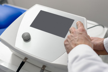 Closeup of male physiotherapist using modern tecar machine
