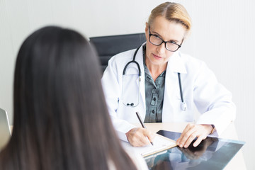 Portrait of senior woman doctor consulting discussing with patient something while sitting at the table. Medicine and health care concept.