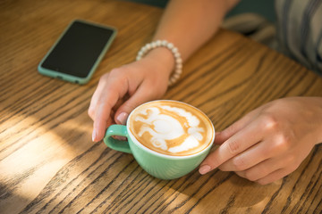 woman in a cafe holds a cup of cappuccino