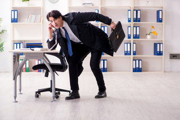 Young male employee in the office in time management concept