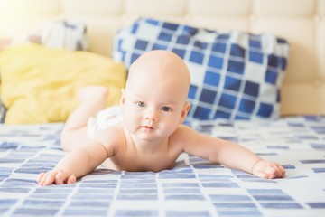 Adorable baby boy in white sunny bedroom. Newborn child relaxing in bed. Nursery for young children. Textile and bedding for kids. Family morning at home