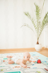 Newborn baby lying on his stomach on the playing Mat with city cars
