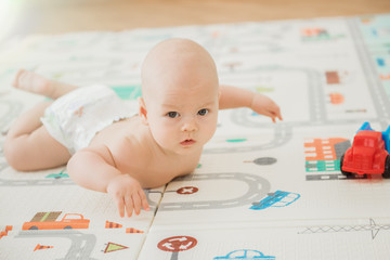 Newborn baby lying on his stomach on the playing Mat with city cars