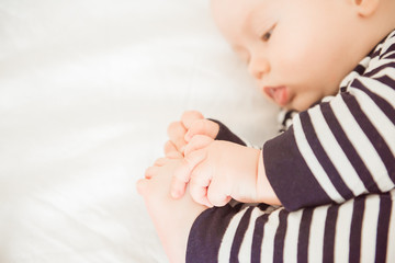 Newborn baby lying in bed in striped clothes